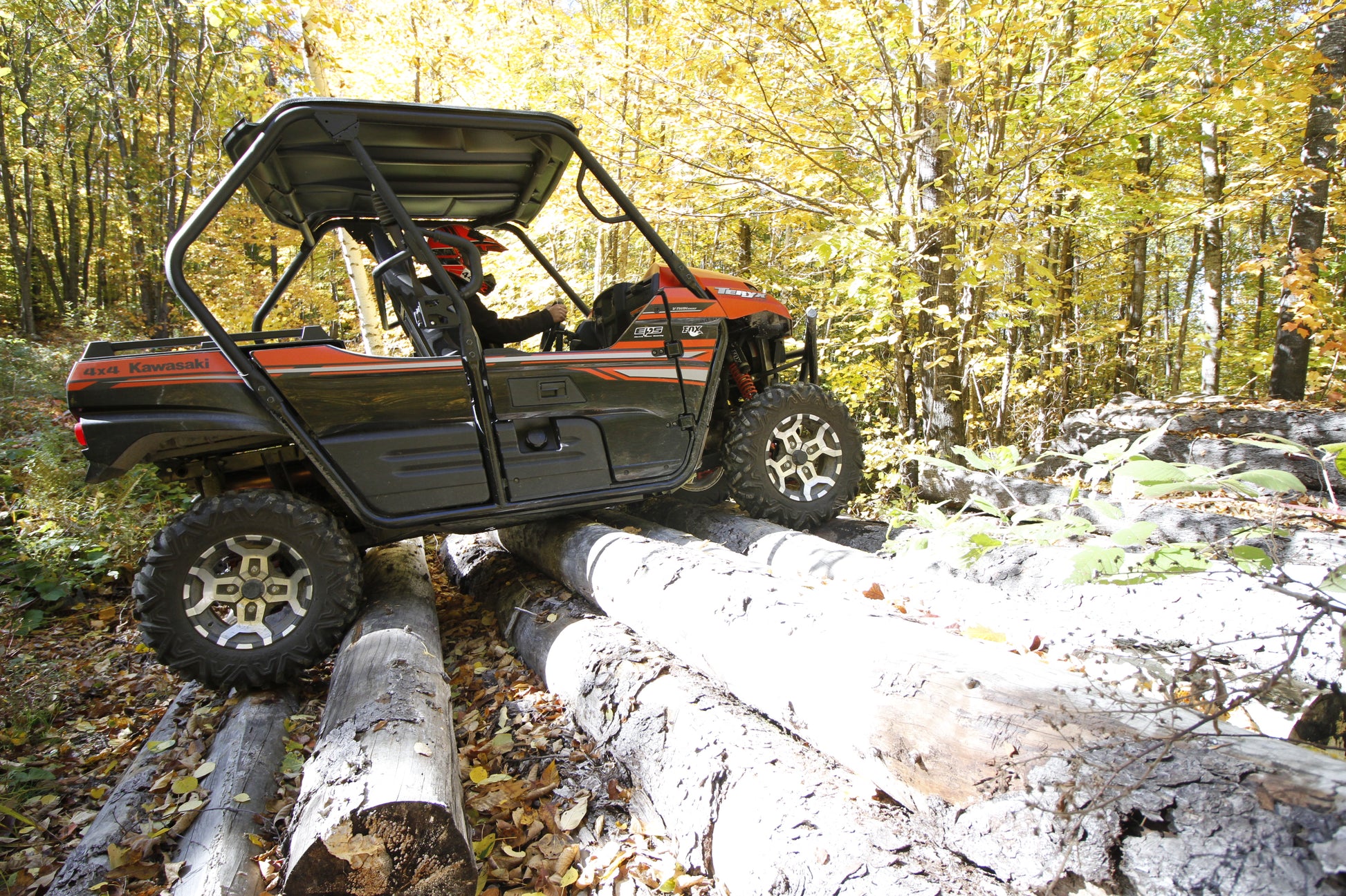 Off-road vehicle navigating logs in a forest setting